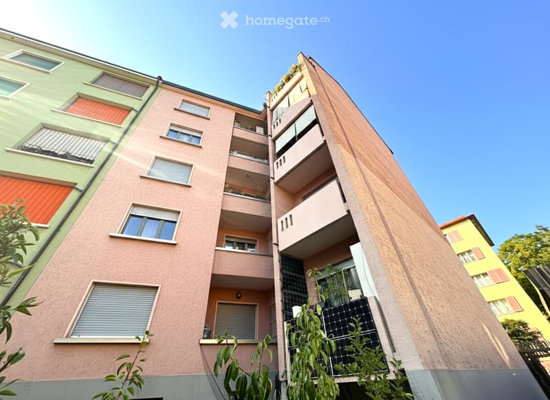 Multi-story residential building with colorful facades, balconies, and solar panels on the roof.