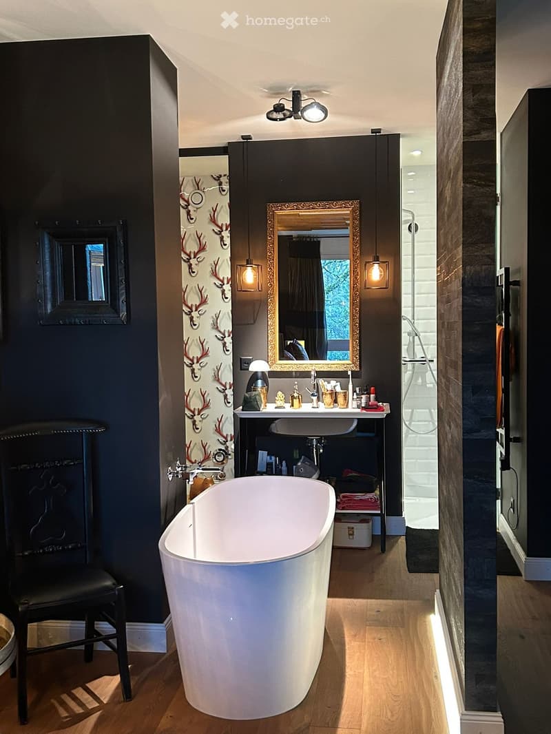 Bathroom with a white bathtub, black walls, wooden floor, a mirror, a sink, and a shower area.
