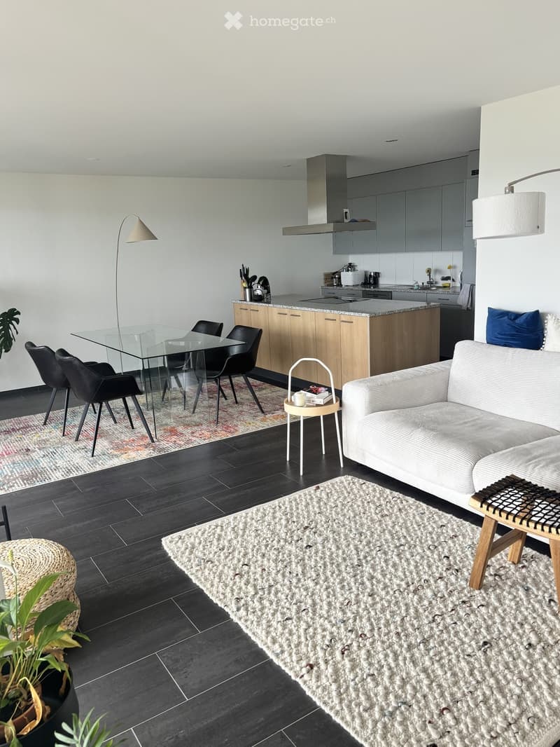 Modern open-plan living and dining area with a sofa, coffee table, dining table with chairs, kitchen island, and floor lamp.