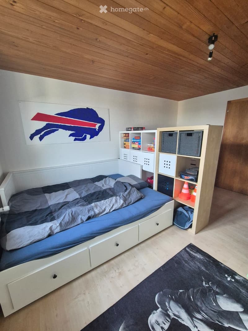 Cozy bedroom with a single bed, built-in storage unit, and a large sports-themed picture on the wall.