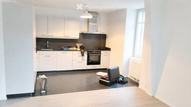 Empty kitchen with white cabinets, stainless steel appliances, and dark tiled floor. No furniture or equipment present.