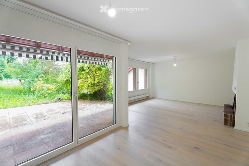 Empty room with wooden flooring, large sliding glass doors leading to a patio, and white walls.
