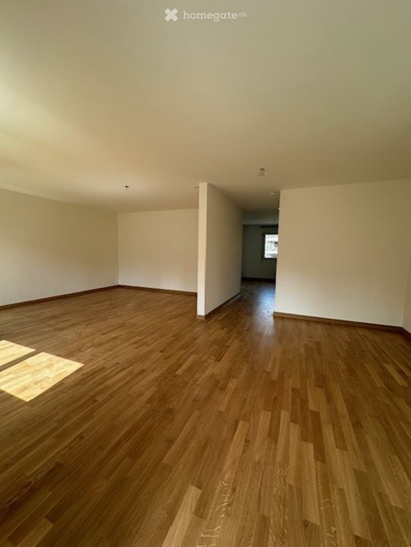 An empty room with hardwood floors and white walls. There are no visible objects or furniture.