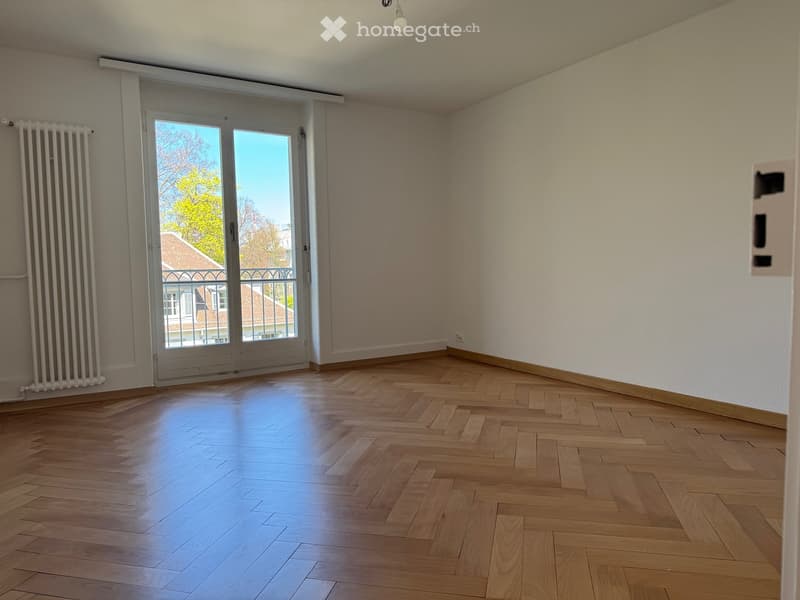 empty room, wooden floor, white walls, large glass doors leading to balcony, white radiator