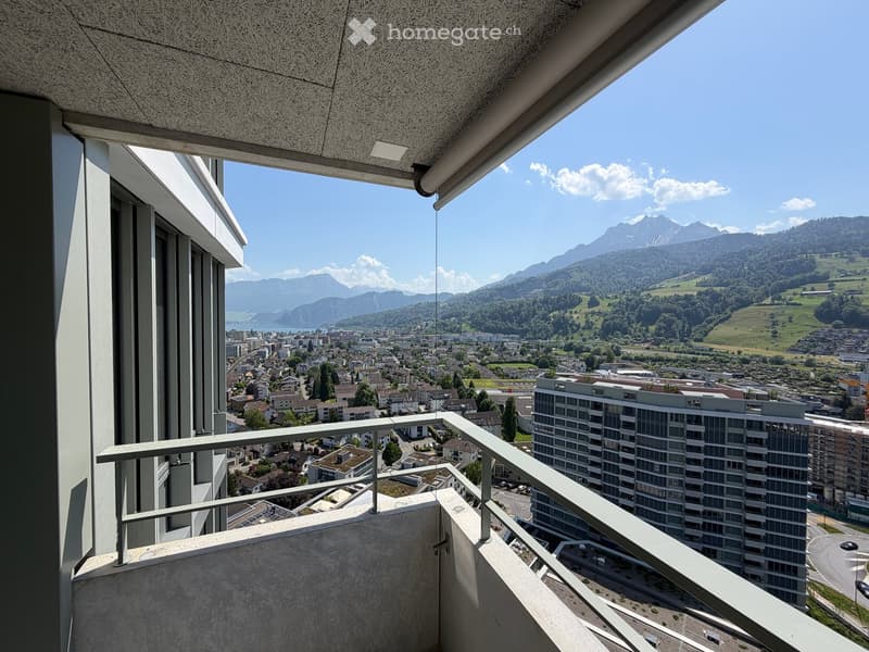 Balcony with metal railing, overlooking a cityscape and distant mountains.