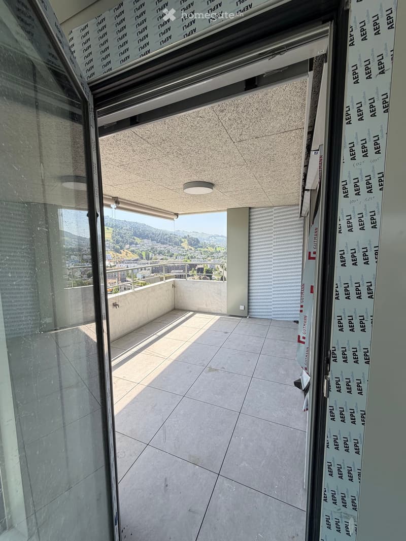 Modern balcony with large glass walls, tiled floor, and a scenic mountain view.
