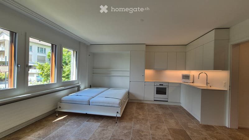small room with bed, microwave, oven, sink, open shelves, windows