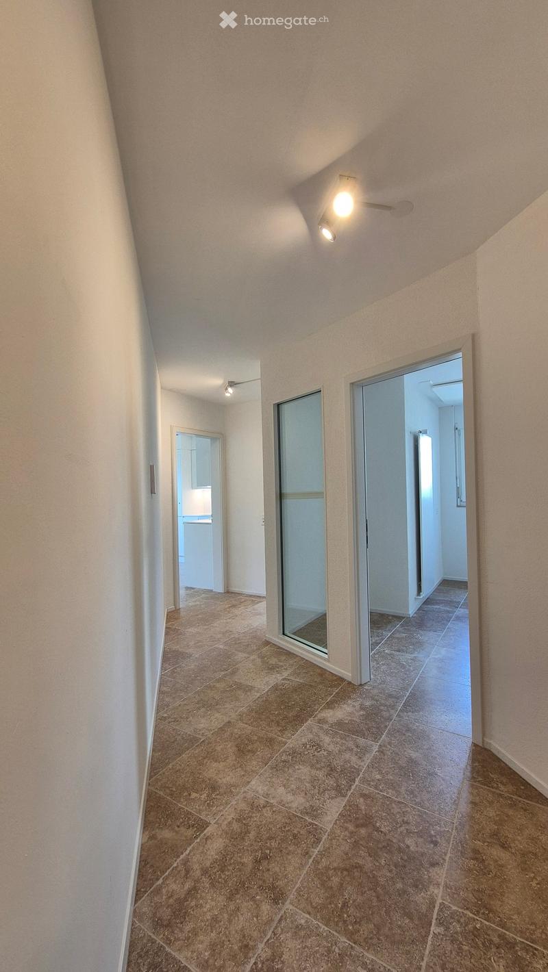 tiled floor, white walls, two ceiling lights, glass doors to other rooms