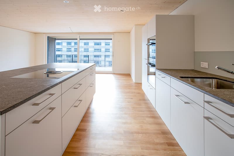 Modern kitchen with white cabinets, granite countertops, and a stainless steel sink. Features a built-in oven and ample natural light from a large window.