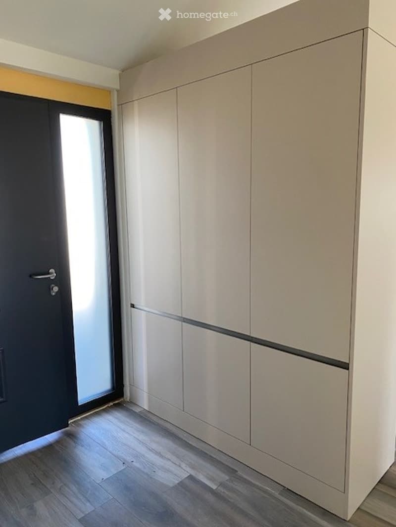 A room with a large white wardrobe, a black door, and a glass door.