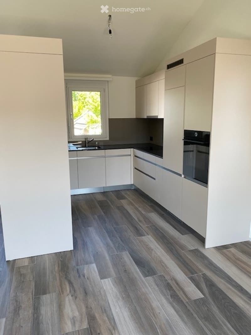modern kitchen with white cabinets, wooden floor, black countertops, stainless steel sink, oven, window
