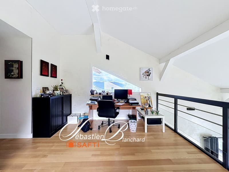 Bright, airy room with wooden flooring, large window offering a scenic view, and modern furnishings including a desk, chair, and cabinet.