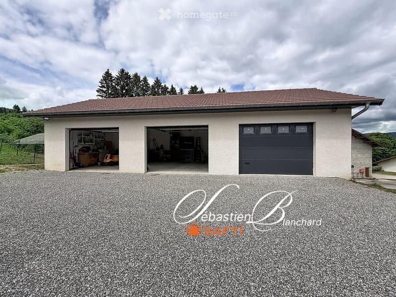 A two-car garage with a tiled roof and light-colored exterior walls, featuring two open garage doors and one closed garage door.