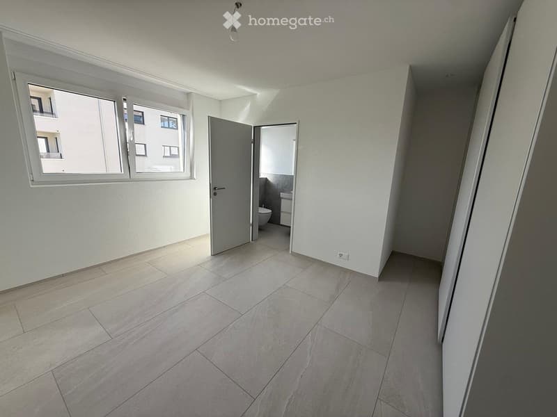 Empty hallway with tiled floor, white walls, and a door leading to a small bathroom with a toilet and sink.