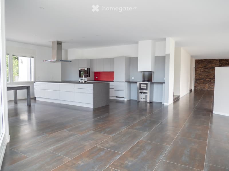 Modern kitchen with white cabinets, stainless steel appliances, a central island, and a dark tiled floor.