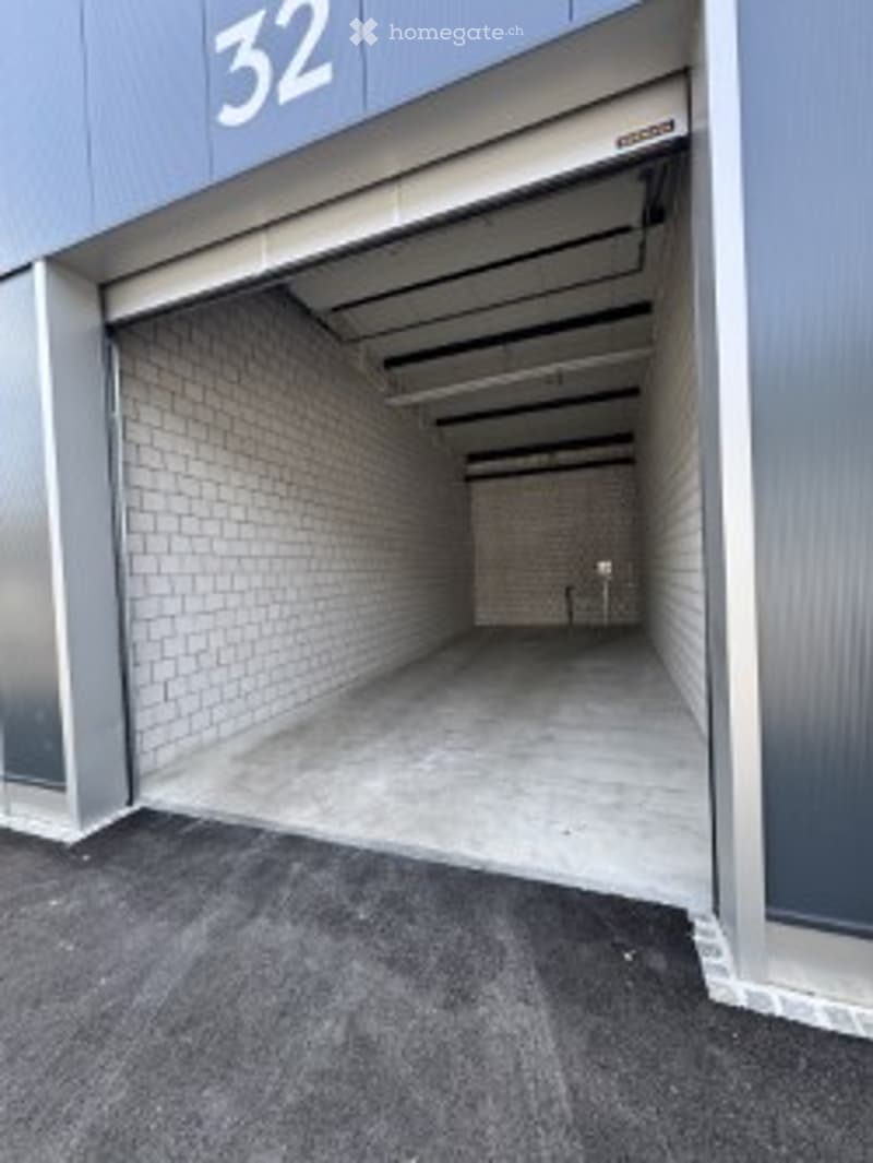 Open garage with concrete floor, brick walls, and industrial ceiling. Number32 displayed above the entrance.