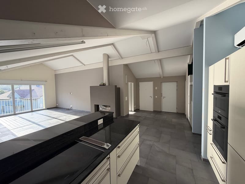 Modern kitchen with black countertop, white cabinets, built-in oven, and stove. Large windows provide natural light.