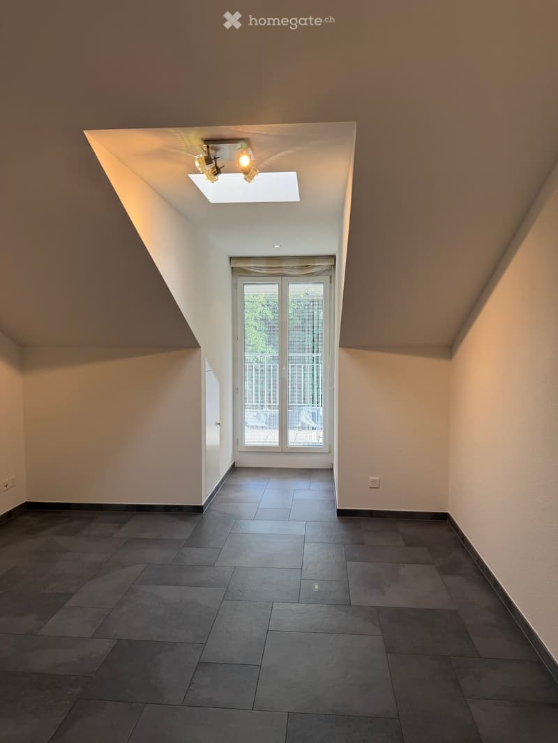 Empty hallway with dark tiled flooring, white walls, and a skylight ceiling fixture. Features a large sliding glass door leading outside.