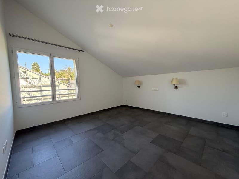 Empty room with grey tiled floor, white walls, large window with view, and two wall-mounted lamps.