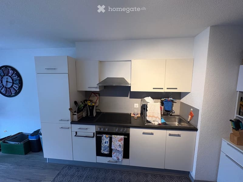 Modern kitchen with white cabinets, stainless steel appliances, and a black countertop.