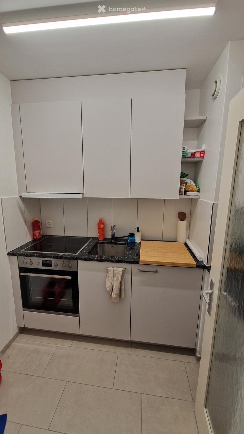 Modern kitchen with white cabinets, stainless steel appliances, granite countertop, and tiled floor.