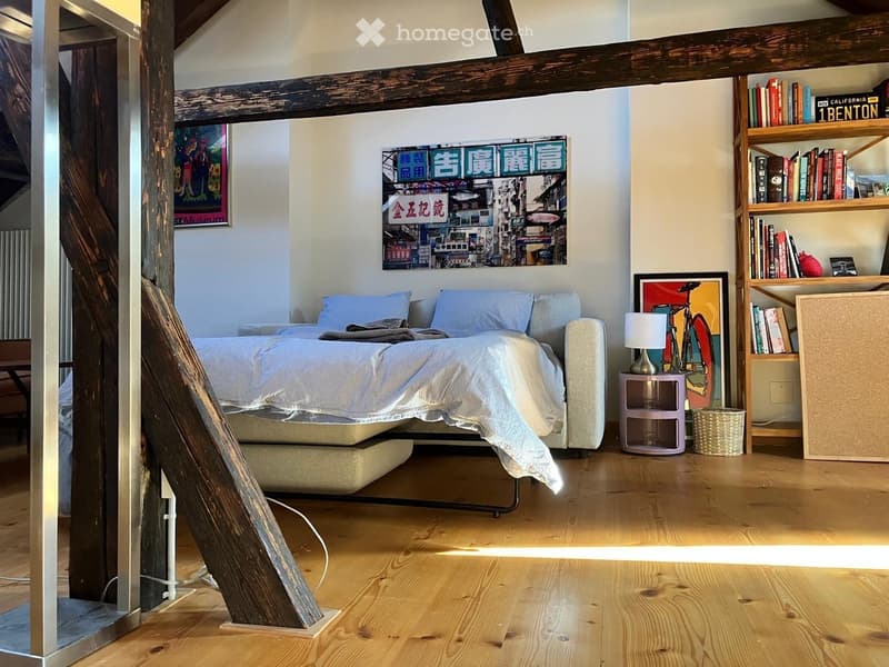 Modern bedroom with a platform bed, nightstand, table lamp, bookshelf, bicycle, and artwork on the walls.
