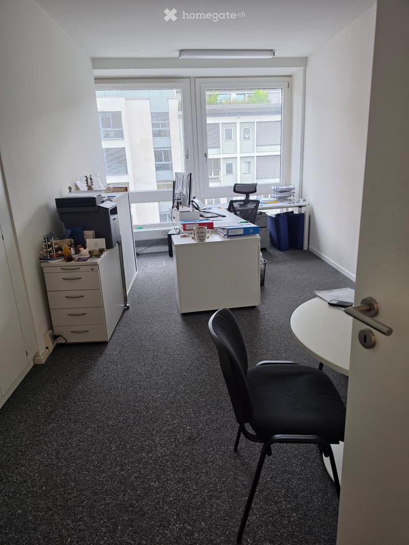 Office space with a desk, chair, printer, and small table near the door.