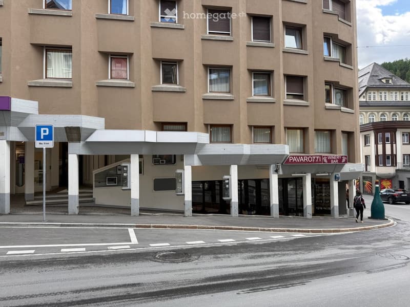 Multi-story building with beige facade, multiple windows, and a covered entrance area. A parking sign is visible on the left, and a sign for "Pavaro Winery Bar" is displayed on the right.
