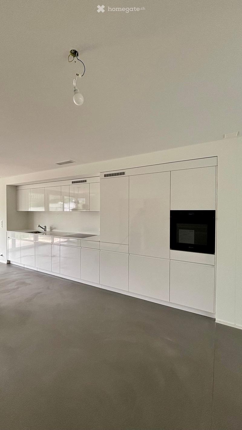 Empty kitchen with white cabinets, stainless steel sink, and built-in oven. No furniture or appliances are present.