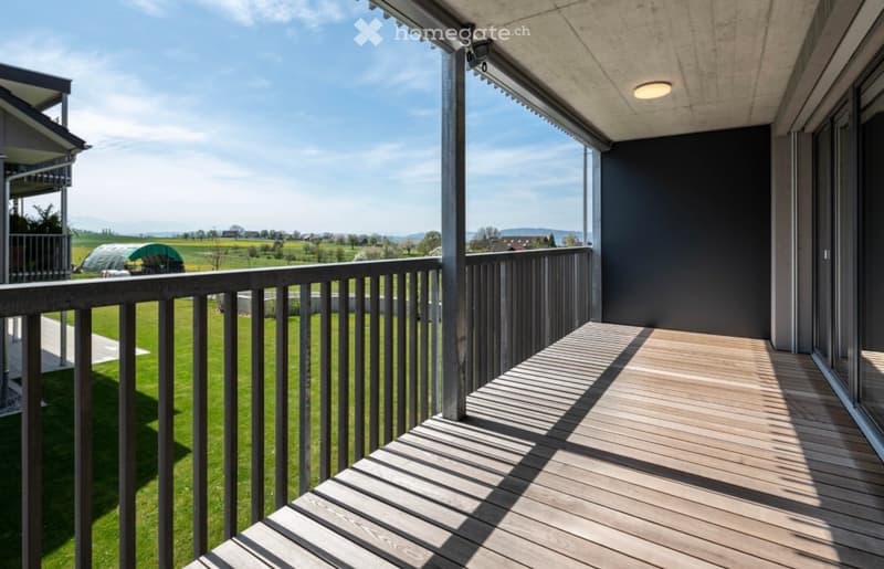 Balcony with wooden decking, metal railing, and scenic countryside view.