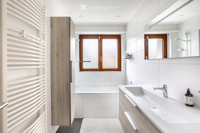 modern bathroom, white tiles, bathtub, sink, mirror, wooden cabinet, white towel, shower head