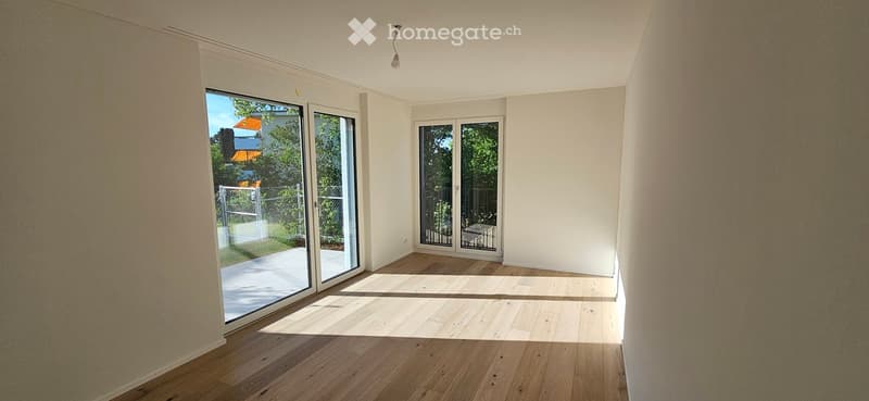 Empty room with wooden flooring, white walls, and large sliding glass doors leading to an outdoor area.