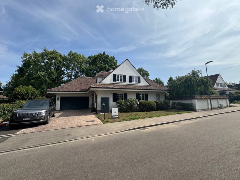 Two-story house with white exterior, dark garage door, and a parked SUV in the driveway.