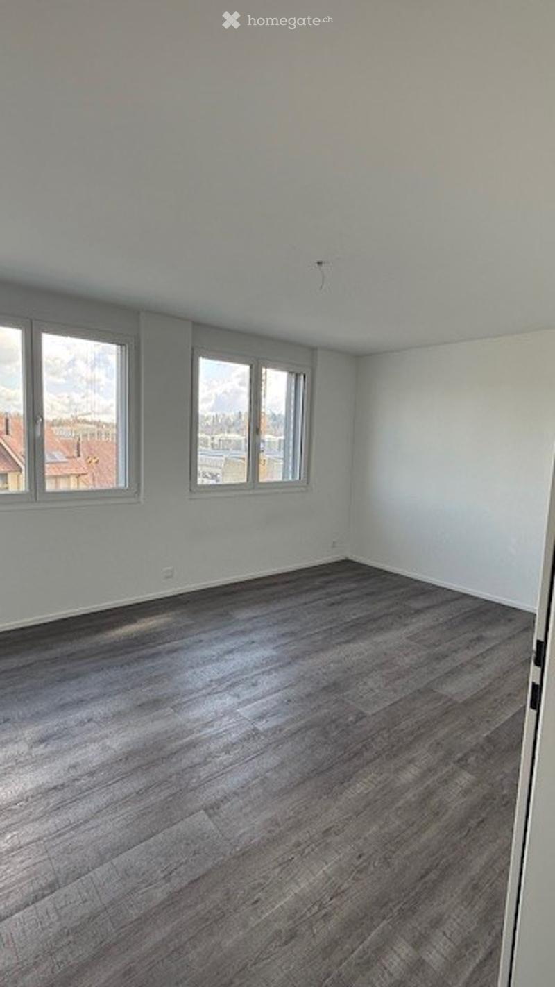 Unfurnished Room. Empty room with wooden flooring, white walls, and large windows offering a view of the city and mountains.