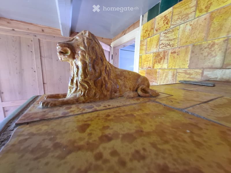 Empty room with a stone lion statue on a platform, wooden walls, and a tiled floor.