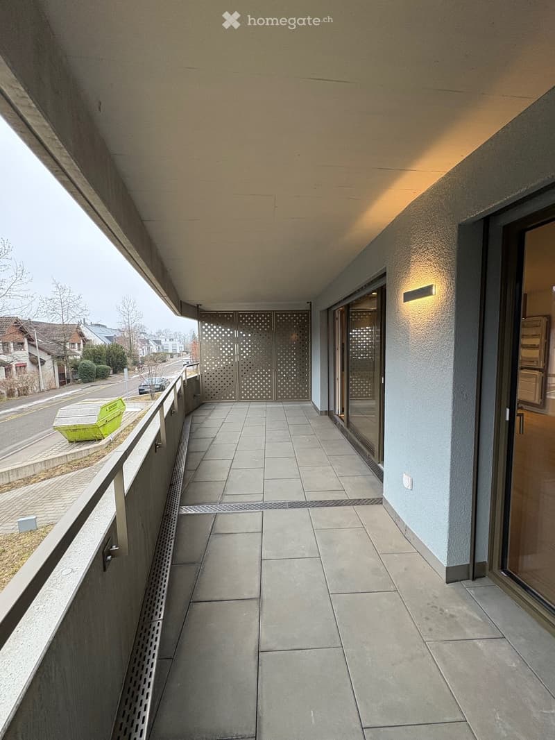 Balcony with tiled floor, metal railing, and a view of the street and surrounding buildings.