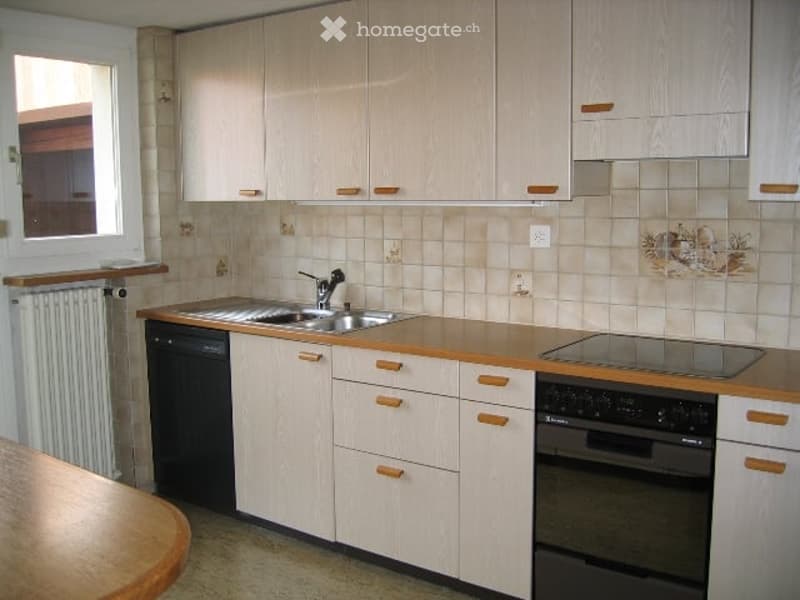 Modern kitchen with light wood cabinets, stainless steel sink and faucet, dishwasher, oven, and countertop.