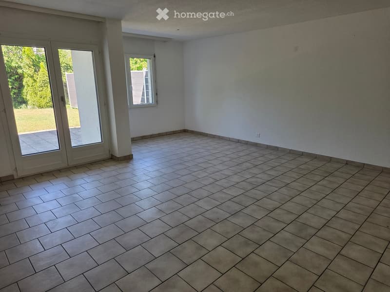 Empty room with tiled floor and white walls, featuring large sliding glass doors and a window, allowing natural light to enter.