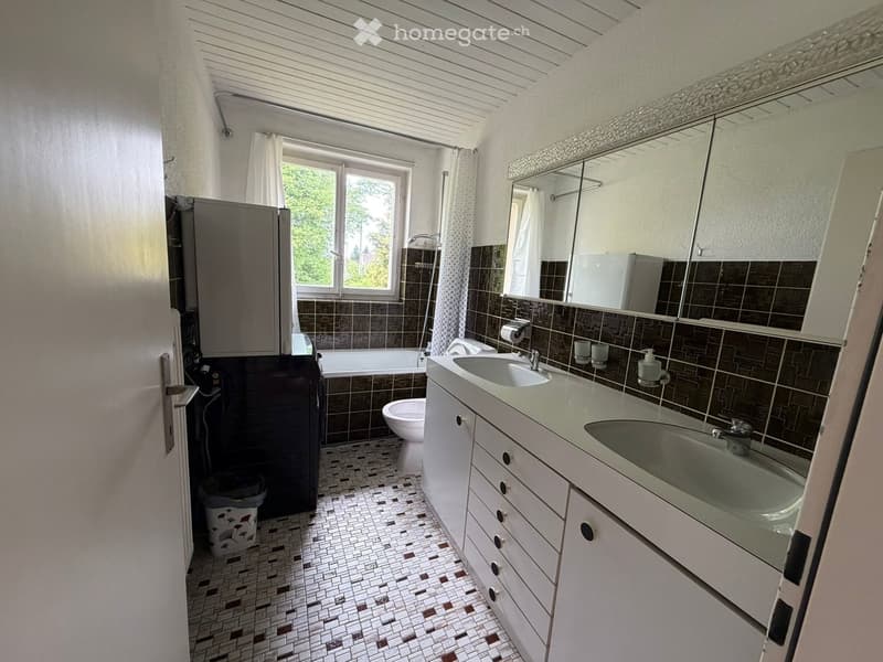 Bathroom with a double sink, mirror, toilet, bathtub, and tiled walls and floor.