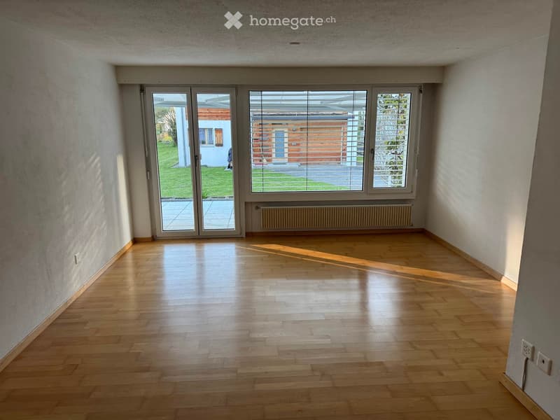 Empty room with wooden flooring, large windows, and a radiator. No furniture or equipment present.