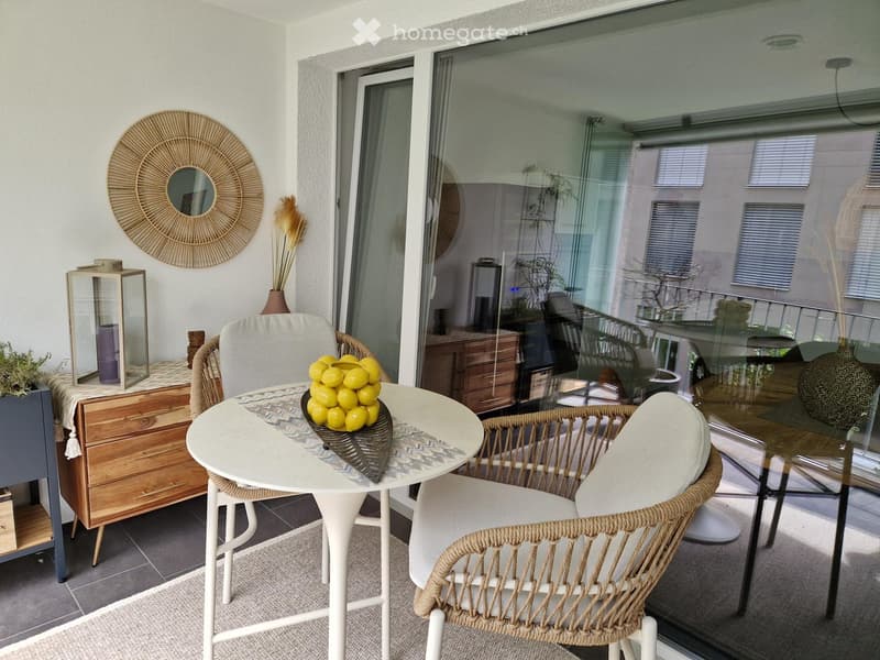 Balcony with a white table, wicker chairs, a vase of lemons, a decorative mirror, and a candle holder.