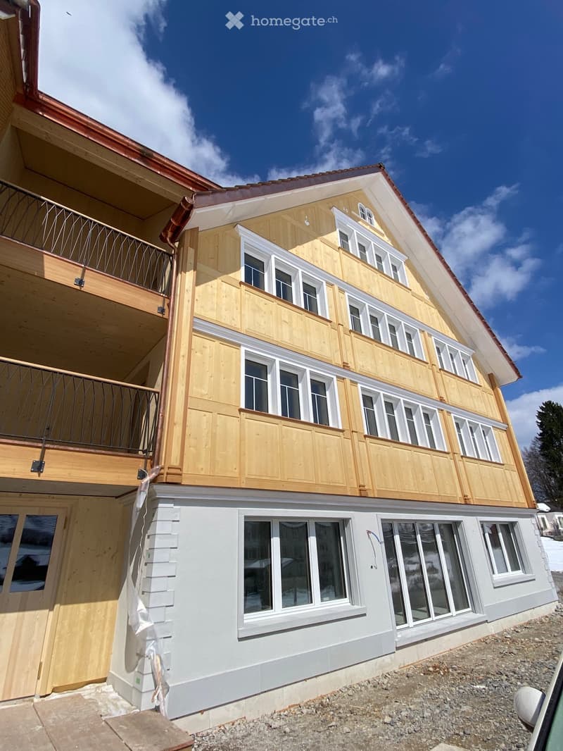 Two-story house with wooden siding and white trim, featuring multiple windows and balconies.
