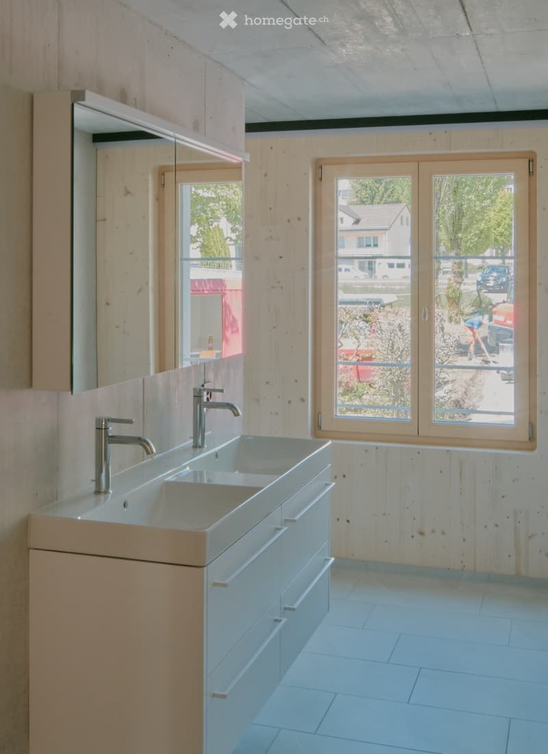 Modern bathroom with double sink, sleek faucets, built-in cabinetry, and large windows offering a view of the street.