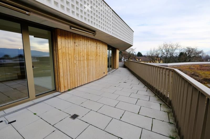 Modern balcony with stone tiles, wooden railing, and glass walls offering a scenic view.