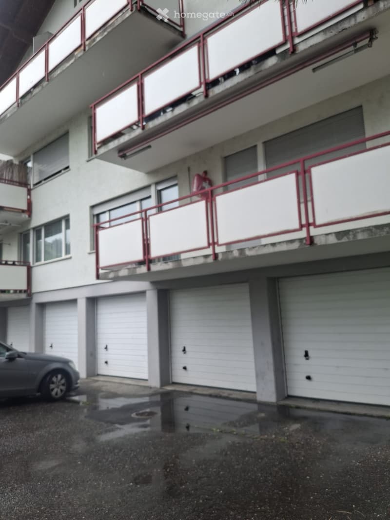 Multi-story residential building with multiple garage doors and balconies with red railings.