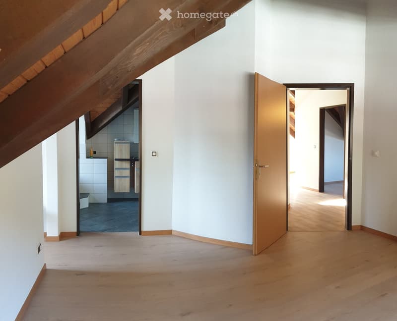 Empty hallway with wooden flooring, white walls, and open doors leading to other rooms.