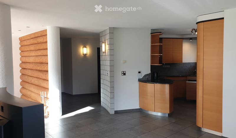 Modern kitchen with light wood cabinets, black countertop, and built-in sink. Features include a sleek design, recessed lighting, and a warm, inviting atmosphere.