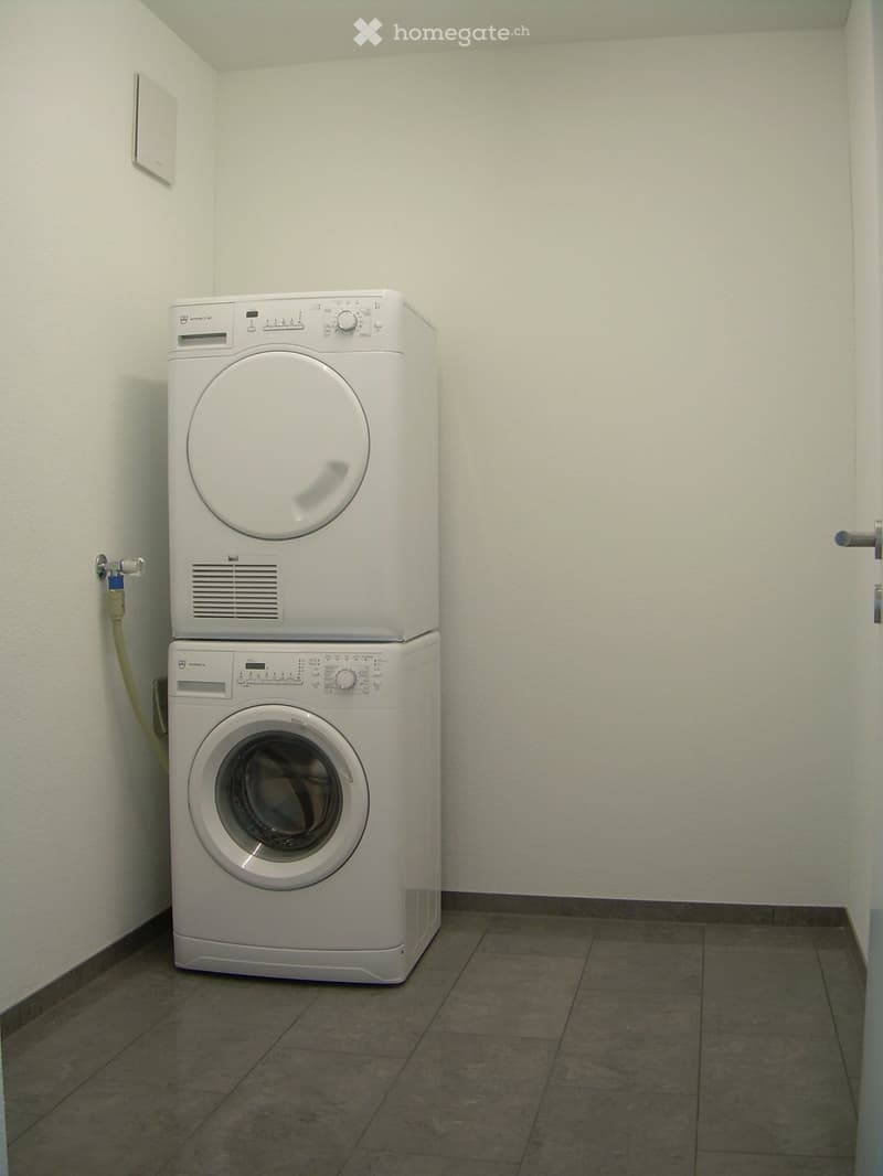 Small bathroom with a stacked washing machine and dryer unit against the wall.