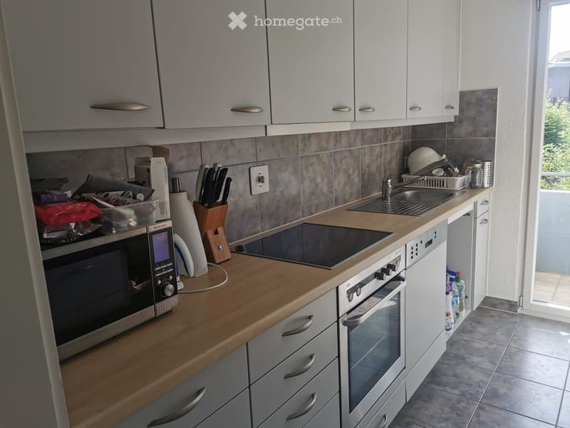 Modern kitchen with white cabinets, wooden countertops, stainless steel appliances, and a sink with a faucet.