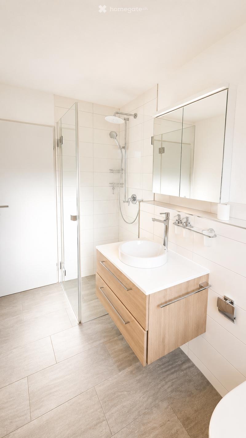 Modern bathroom with a white sink, wooden cabinet, large mirror, and glass-enclosed shower area.